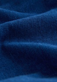 Gros plan sur un tissu bleu foncé montrant une texture fine tricotée et des plis doux.
