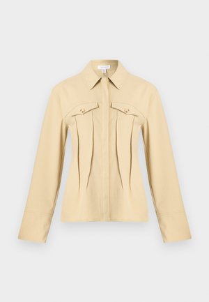 Μπεζ μακρυμάνικο σακάκι με μυτερό γιακά, δύο κουμπωτές θήκες στο στήθος και κάθετες ραφές στο μπροστινό μέρος, τοποθετημένο επίπεδα σε ουδέτερο φόντο.