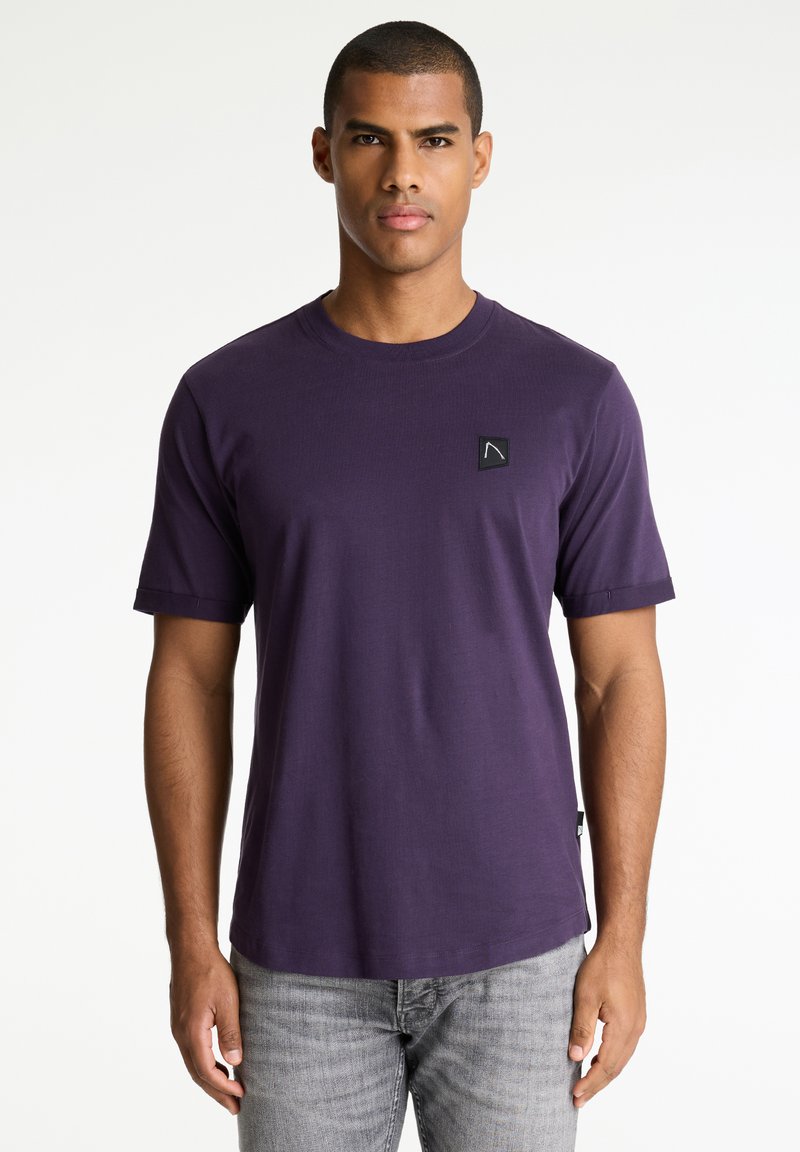 Violet trumpas rankovėmis marškinėliai, pagaminti iš minkštos medžiagos, su apvalia iškirpte ir maža logotipo etiketė kairiajame krūtinės kampe.