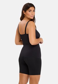 Haut de sport noir avec de fines bretelles et une coupe ajustée, associé à un short noir assorti. Texture lisse et coutures minimalistes.