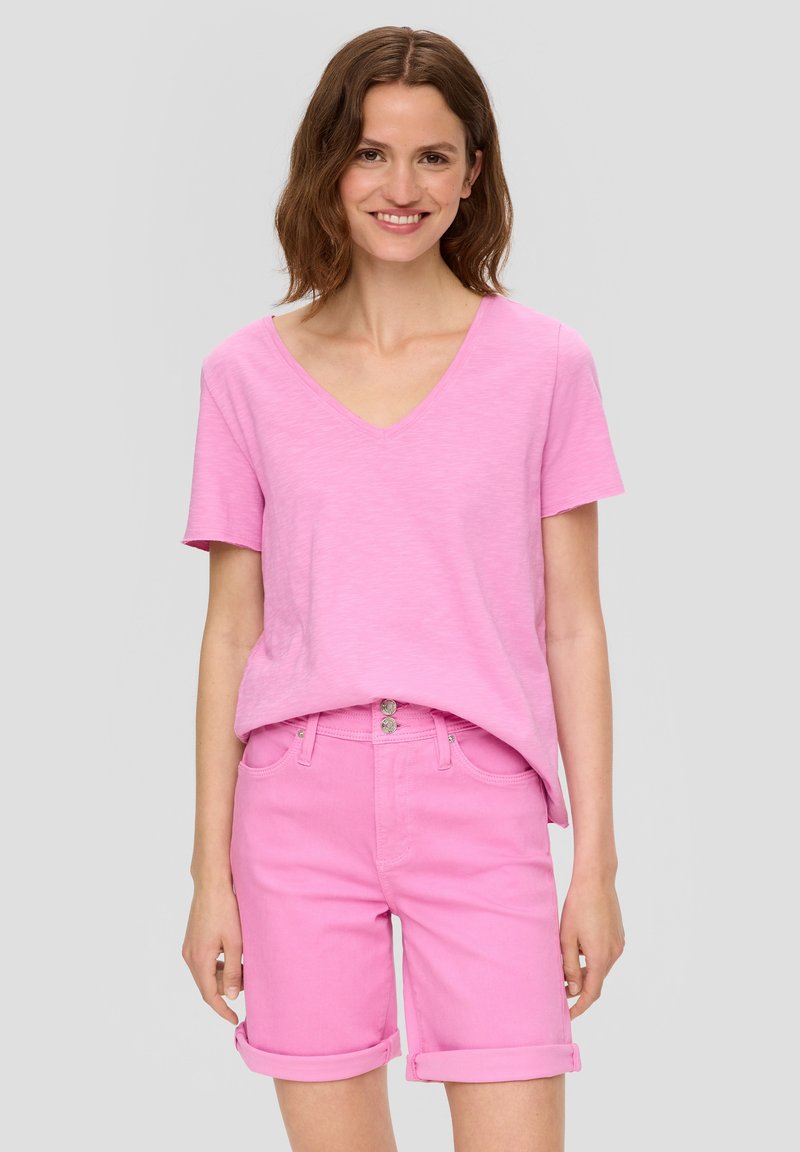 Lichtroze t-shirt met korte mouwen en V-hals, gecombineerd met opgerolde mouwmouwen roze denim shorts met een knoopsluiting en voorzakken.