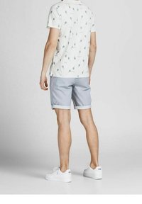 Bílý tričko s krátkým rukávem a šedým potiskem balónu, doplněné o světle šedé šortky s ohrnutým lemem. Nosené s bílými teniskami.