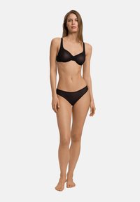 Set di lingerie nera composto da un reggiseno liscia e senza cuciture con spalline larghe e slip a vita bassa coordinati, entrambi realizzati in tessuto morbido e elasticizzato.
