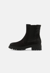 Botas negras de tobillo con parte superior de ante texturizado, paneles laterales elásticos y suela resistente, que presentan un acento decorativo acolchado en el talón.
