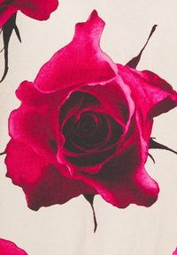 Rose rouge aux bords sombres sur un fond beige clair. Les pétales sont lisses, détaillés et superposés, mettant en valeur la forme naturelle de la fleur.