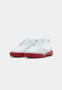 Zapatos de fútbol sintéticos blancos con un upper acolchado, suela de goma roja y acentos reflectantes. Cuenta con un diseño tradicional de cordones.