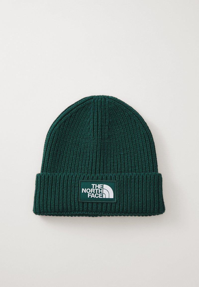 Zöld kötött sapka bordázott textúrával és hajtott szegéllyel. Fehér "The North Face" logóval ellátott téglalap alakú folt található rajta.