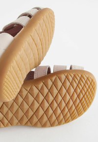 Strappy sandalen in lichtroze leer met een gestructureerde rubberen zool die een diamantpatroon heeft voor grip en ondersteuning.