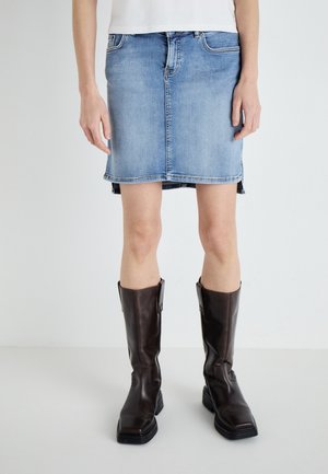 Denim miniskjørt i lys blå med rett snitt, frontlommer og råkant. Kombinert med brune skinnstøvler til kneet.
