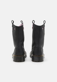 Stivali alla caviglia in pelle nera con finitura testurizzata, con accenti rosa e linguette per l'estrazione. Suola in gomma nera spessa con cuciture gialle.