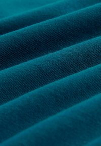 Zilā auduma ar gludu tekstūru, ar vienmērīgi izvietotiem, paralēliem krokām, kas veido viļņveidīgu izskatu. Nav redzamu rakstu vai akcentu.