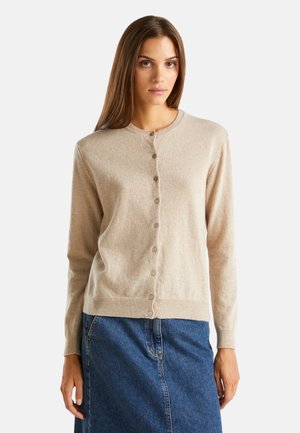 Gilet beige avec un col rond, des manches longues et une fermeture à six boutons à l'avant. Fabriqué en matériau doux et texturé.