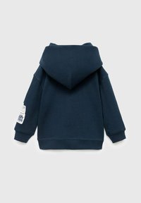 Tmavě modrá mikina s velkou kapucí, žebrovanými manžetami a lemem. Obsahuje design nášivky na levém rukávu. Měkká, texturovaná látka.