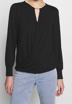 Haut noir avec un décolleté rond, détail en goutte d'eau et devant drapé. Manches longues avec des poignets ajustés, fabriqué dans un tissu doux et lisse.