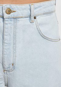 Bermudas de mezclilla azul claro con una cinturilla resistente, botón de logo dorado, bolsillos frontales y detalles de costura visibles. Textura suave.