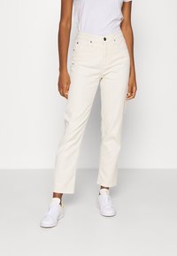 Krämfärgade jeans med raka ben tillverkade av denim, med fem fickor, metalldetalj i knäppning och minimalistiska söm-detaljer.