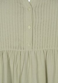 Light green button-up dress with vertical pleats, gathered waist, and smooth, textured fabric. Features a V-neck and two buttons at the top.