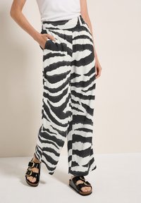 Pantalons amples en tissu léger, présentant un motif de rayures zèbres noir et blanc et une taille élastique avec des poches latérales.
