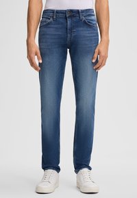 Jasnoniebieskie dżinsy o prostym kroju, z pięcioma kieszeniami i delikatnym wyblaknięciem. W połączeniu z białymi trampkami.