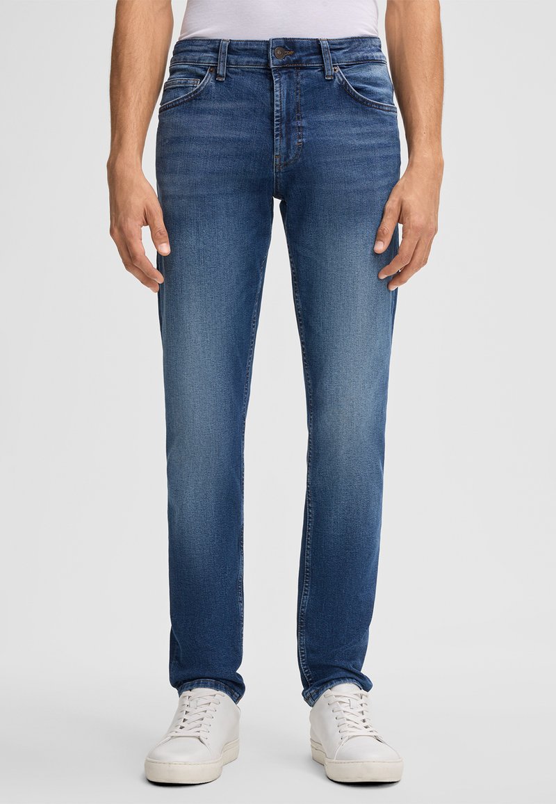 Jasnoniebieskie dżinsy o prostym kroju, z pięcioma kieszeniami i delikatnym wyblaknięciem. W połączeniu z białymi trampkami.