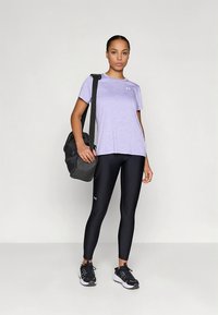 Fialové ľahké tričko, čierne priliehavé legíny, čierne tenisky a čierna kabelka na rameno. Jednoduchý dizajn s atletickými značkovými detailmi.