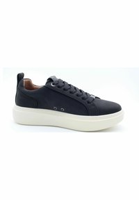 Sneaker in pelle nera con punta rotonda, suola bianca spessa e design elegante con dettagli a contrasto di lacci e occhielli.