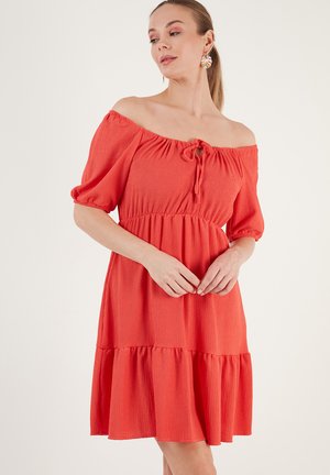 Red off-the-shoulder dress with a tie detail at the neckline, short puff sleeves, and a tiered skirt in a textured fabric.
