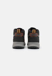 Czarne wysokie sneakersy z brązowymi akcentami, szarymi podeszwami i siateczkowymi detalami. Posiadają uchwyty do zakładania i teksturowany materiał dla lepszego wsparcia.