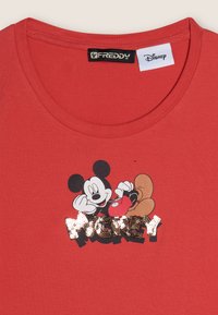 T-shirt en coton rouge avec un graphisme de Mickey Mouse et du texte en sequins indiquant "MICKEY". Manches courtes et col rond.