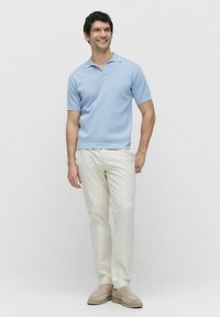 Ljusblå kortärmad polotröja, krämfärgade byxor och beige slip-on skor. Slätt tyg, enkel design, avslappnad passform.