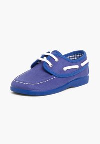 Zapato de barco de lona azul con cordones blancos, forro interior a cuadros y costuras en contraste. Punta redondeada y suela de goma.