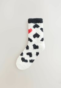 Lodden hvid sok med sorte hjerteformede pletter og rødt hjerteaccent. Har en kontrastfuld sort manchet øverst. Blød tekstur.
