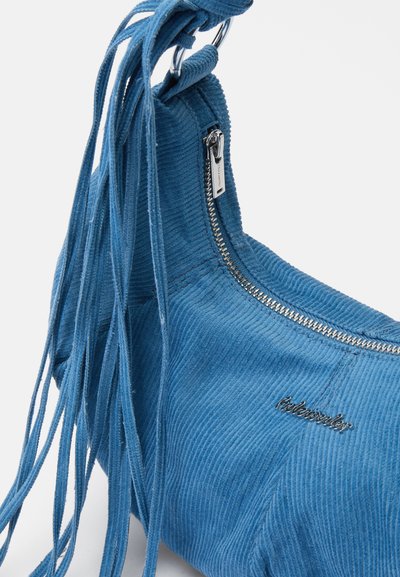 Blauwe corduroy handtas met franjes, rond formaat, zilveren rits hardware en geborduurd logo. Getextureerd oppervlak met verticale ribbels.