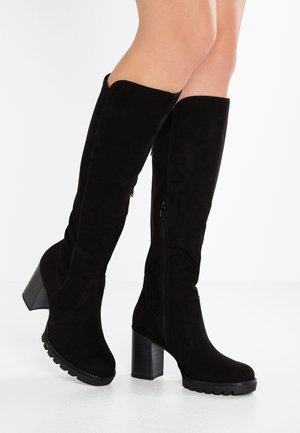 Czarne zamszowe kozaki za kolano z masywnym obcasem w stylu block heel, zapinane na suwak z boku, z teksturowaną podeszwą dla lepszej przyczepności. Gładkie wykończenie i elegancki design.