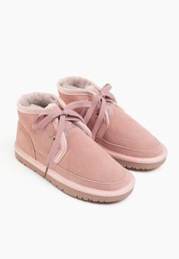Stivaletti alla caviglia in suede rosa con fodera morbida, punta rotonda e lacci abbinati. Presentano occhielli dorati e una suola in gomma testurizzata.