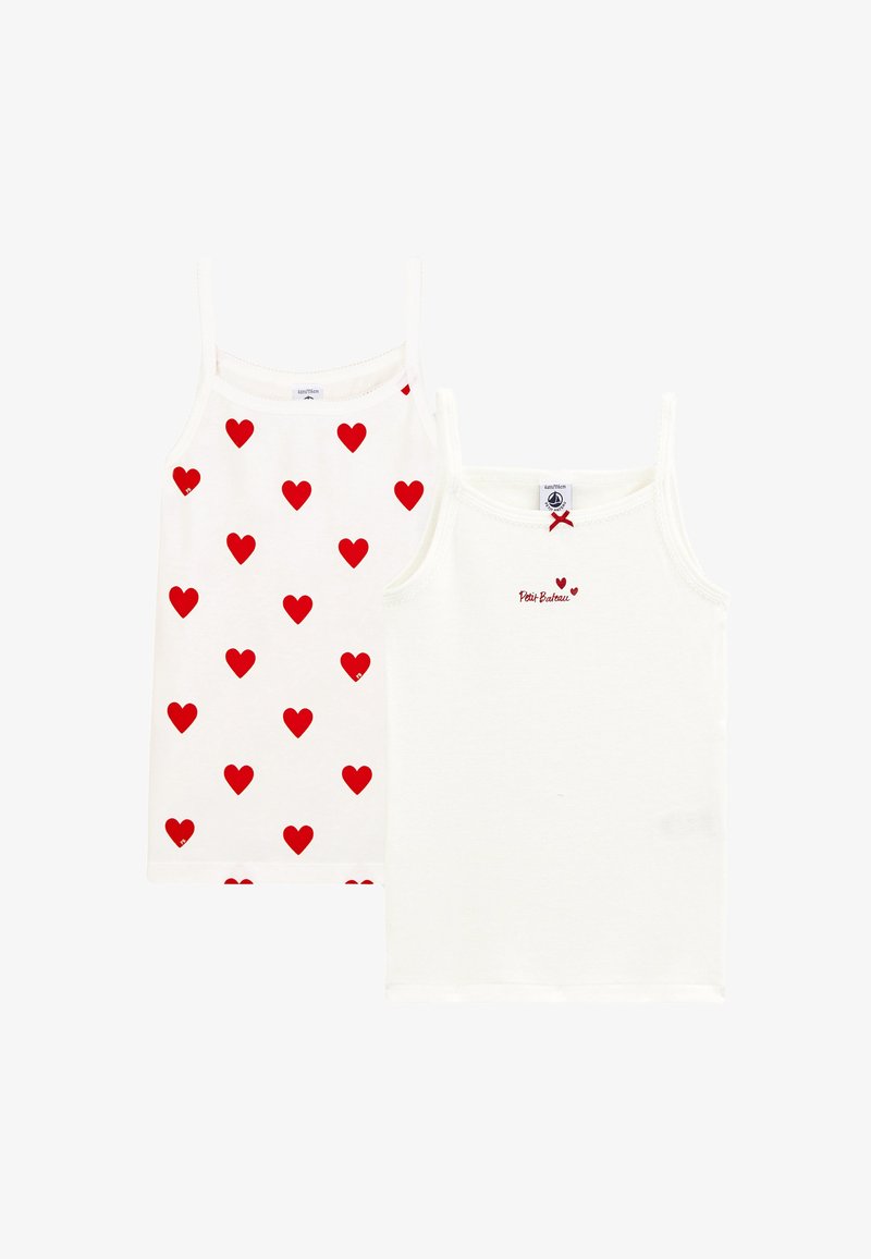 Dve beli otroški brezrokavnik, eden z vzorcem rdečih src, drugi enobarven z majhnimi rdečimi pentljami in napisom "Petit Bateau".