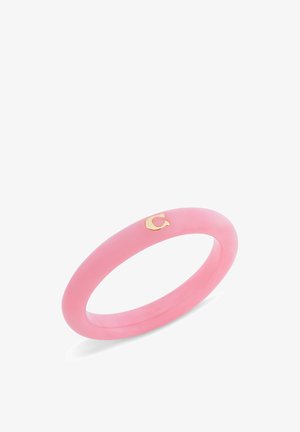 Bracelet jonc en résine rose avec un petit détail lettre « C » en or sur fond blanc.