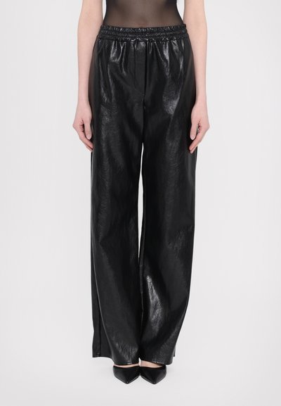 Black, high-waisted, wide-leg pants made from shiny, textured material; elastic waistband; paired with pointed black shoes.