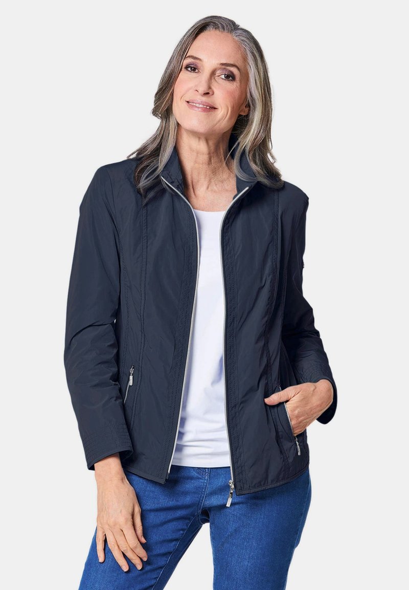 Leichte marineblaue Jacke mit Stehkragen, Frontreißverschluss und zwei seitlichen Taschen; zeichnet sich durch eine glatte Textur und subtile Nähte aus.