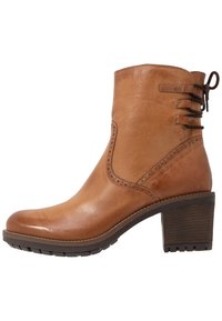 Hnědá kožená kotníková obuv s kulatou špičkou, dekorativním šněrováním na boku a zúženým, texturovaným podpatkem. Měkký povrch a hladký vzhled.