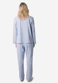Niebiesko-biały, paskowany komplet piżam z długimi rękawami i spodniami, o luźnym kroju i miękkiej fakturze tkaniny.