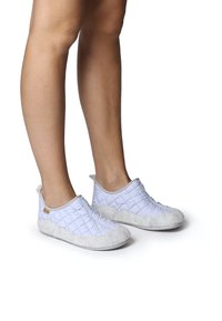 Quiltade ljusblåa slip-on skor med en mjuk grå mockadetalj vid tån och hälen, med elastiska sidopaneler för enkel påtagning.