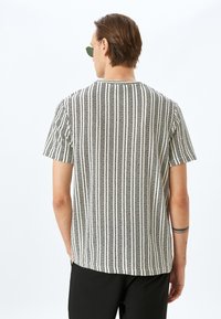 Camisa de manga corta con un patrón texturizado a rayas en blanco y negro, con cuello redondo y un corte relajado.