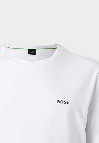 T-shirt blanc à col rond avec petit logo noir "BOSS" sur la poitrine gauche et une étiquette intérieure du col bordée de vert indiquant également "BOSS".