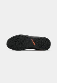 Suela de zapato deportivo negro con superficie texturizada, con marca en color naranja. Material de goma que proporciona agarre y durabilidad. Diseño ligero.