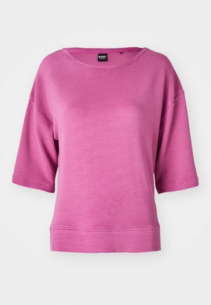 Rosa t-shirt med kort ärm och rund hals, ribbad textur och en avslappnad passform. Har sänka axelsömmar och rak fåll.