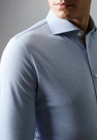 Lichtblauwe lange mouwen shirt met een gestructureerde kraag, knoopdetails en een gladde, textuurstof. Close-up van het bovenste kledingstuk.