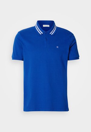 Polo bleu en coton, doté d'une patte de boutonnage à trois boutons, d'un col rayé blanc et d'un logo brodé sur la poitrine.