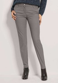 Grijze op maat gemaakte broek met slim fit, voorzakken en een gladde textuur, gecombineerd met zwarte hoge enkellaarzen.