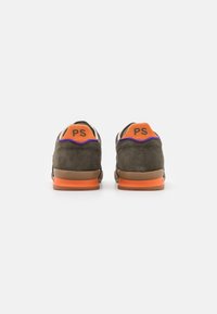 Dunkelgrüne Wildledersneaker mit orangefarbenen Fersenakzenten, lila Nähten und Gummisohle. Mit "PS"-Logo auf der Rückseite.